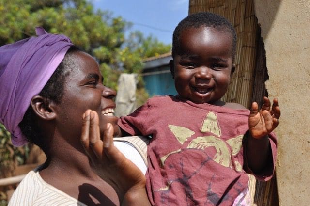 A joyful woman holds a child, both sharing a tender moment filled with smiles and warmth.