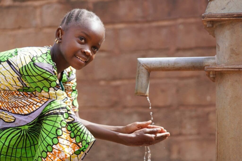 A young girl joyfully holds a water pump, demonstrating her engagement with outdoor play and exploration.